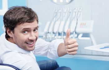 man during the dentist procedure with a thumb up